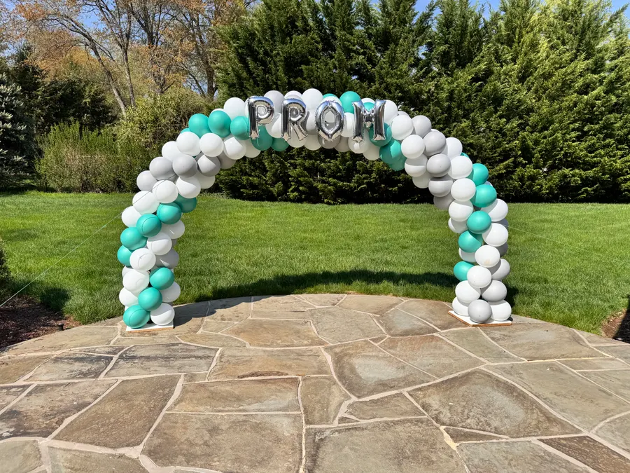 Prom balloon arch in teal and white on a garden patio