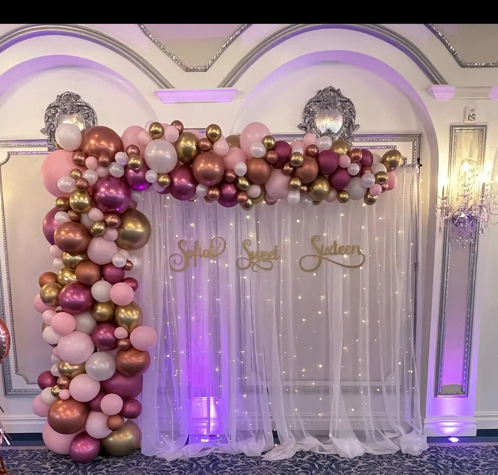 Pink, burgundy and gold balloon garland framing a sweet sixteen backdrop